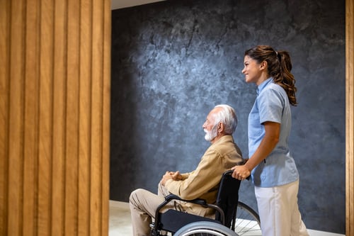 modern-nursing-home-female-nursing-assistant-taking-care-elderly-man-wheelchair