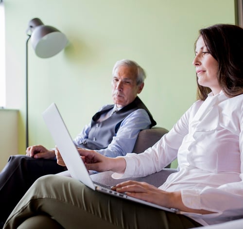 senior-businessman-looking-woman-working-laptop