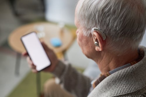 senior-man-with-hearing-aid-using-smartphone